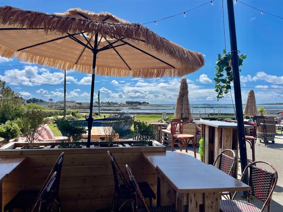 Terrasse avec parasols en paille face à la baie